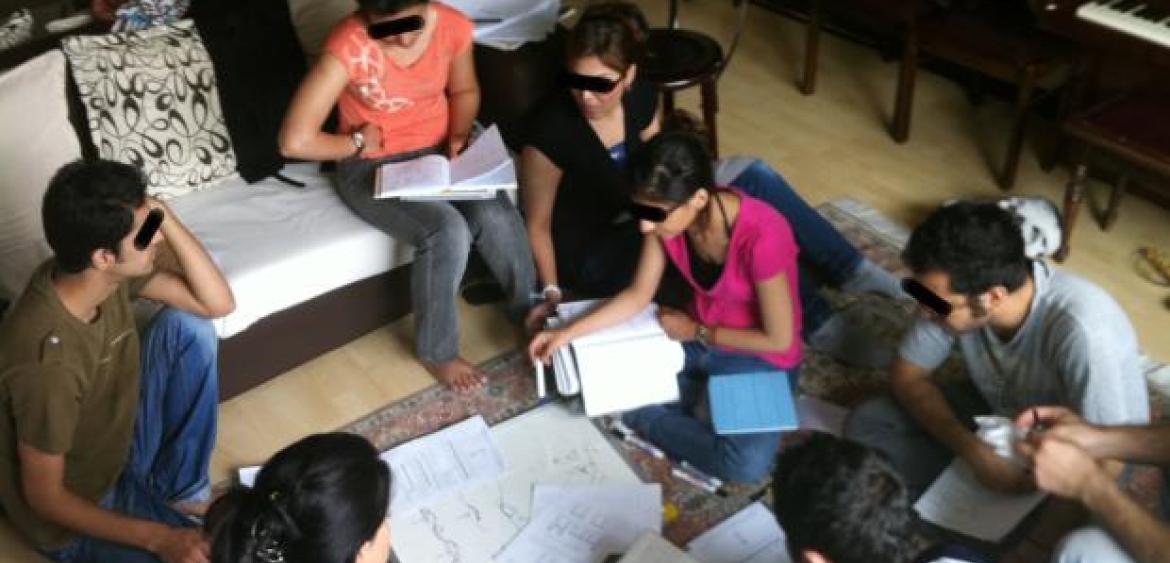 Studierende des Bahá’í Institute for Higher Education bilden sich heimlich im Wohnzimmer weiter (2009). Foto: Niknaz Aftahi. via Wikimedia Commons (https://commons.wikimedia.org/wiki/File%3AIranian_BIHE_students_in_a_living_room.jpg). Lizenz: CC BY-SA 4.0