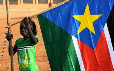 A girl raising the flag of South Sudan. Image: Wikimedia (CC)