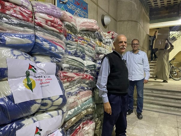 Zwei Mitglieder des Volkskomitees für Solidarität mit Palästina vor den Decken, die sie für ihren Hilfskonvoi nach Gaza gesammelt haben. Foto: Jana Treffler.