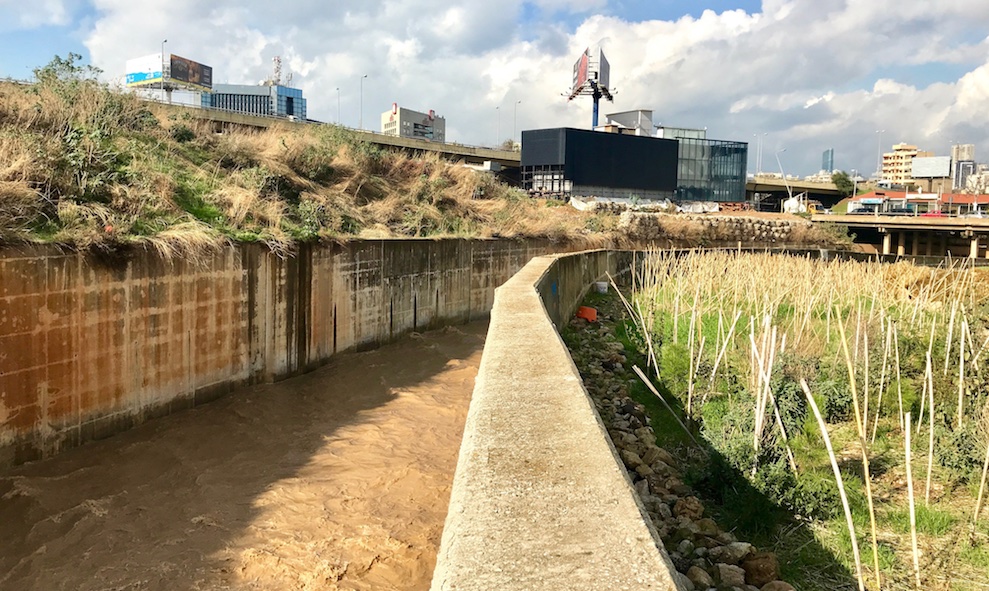 Der kanalisierte Fluss nach Starkregen und die angrenzende Aufforstungsfläche. Die Bambusstöcke kennzeichnen die Baumsetzlinge. Bild: Bruna Rohling, Beirut, Dezember 2021